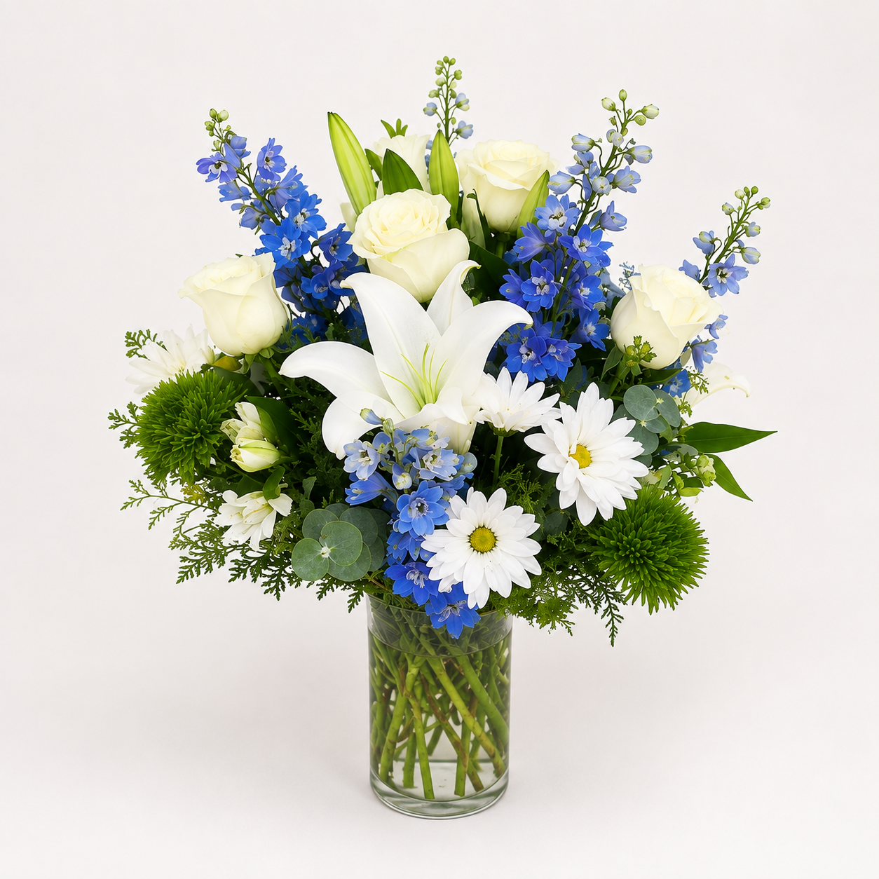 Blue and white floral arrangement with white lilies and roses, blue flowers, and fresh greenery