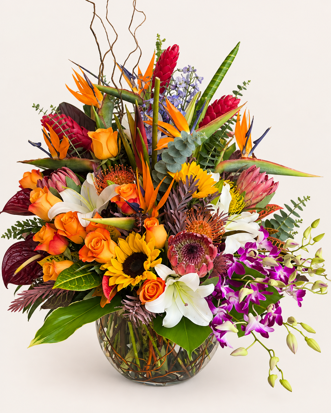 Tropical Majesty luxury tropical flower arrangement featuring bird of paradise, protea, orange roses, white lilies, sunflowers and purple orchids in a glass vase.
 Copy